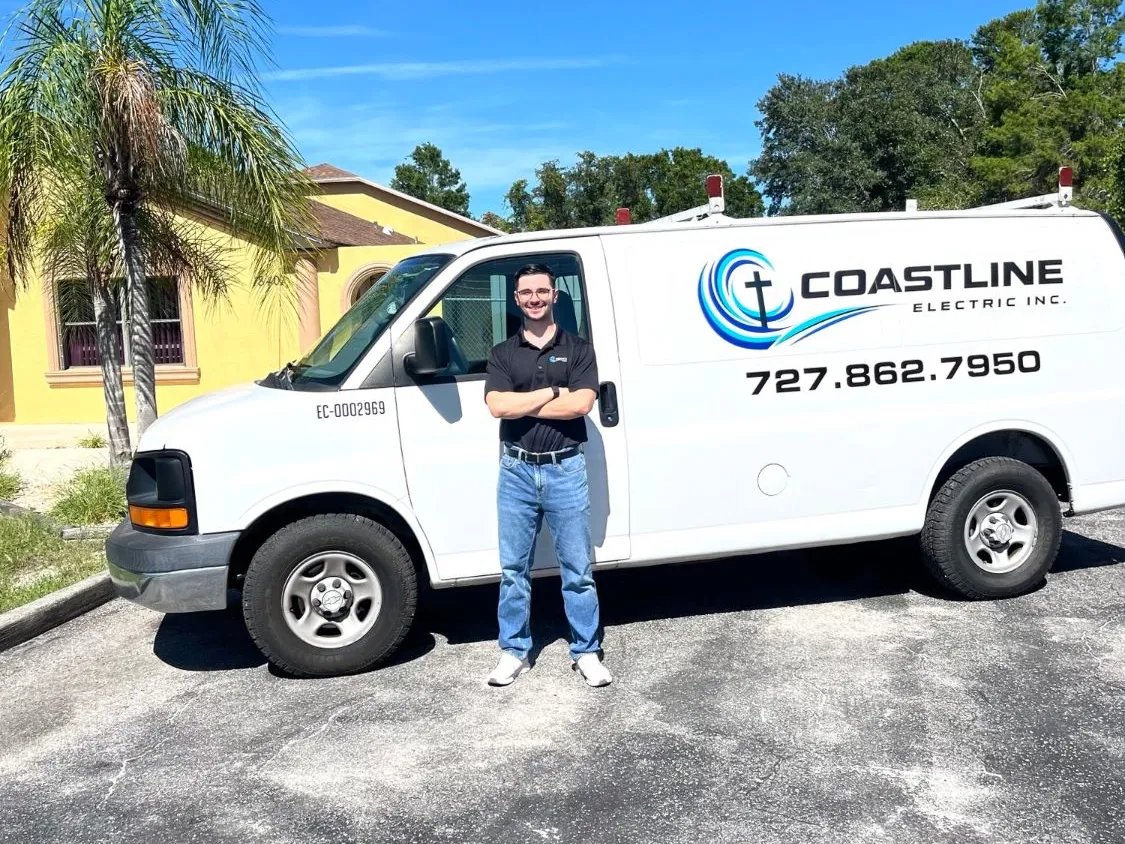 A Coastline Electric Inc. team member standing in front of a company service van outside the office in Hudson, Florida