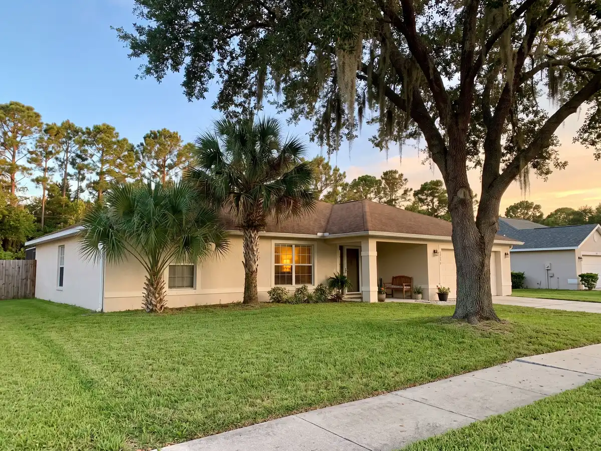 Single-storey Florida ranch home with a live oak and palm trees in warm evening light, the kind of house found throughout Spring Hill