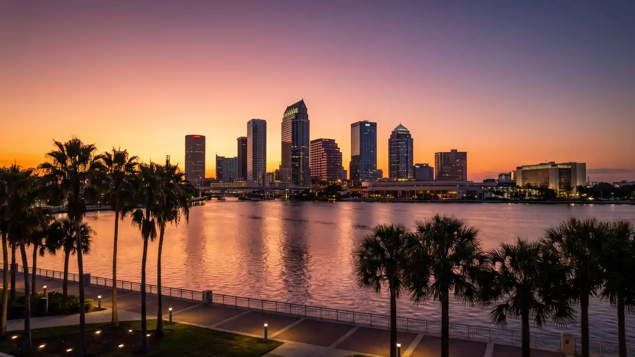 Downtown Tampa skyline across the water at sunset with palms along the riverwalk